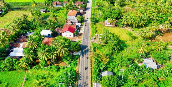 A stunning aerial view of a tropical rural landscape featuring lush greenery and a winding road.
